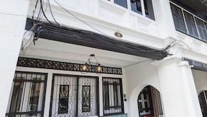 A white building with a balcony, black railings, and a decorative light fixture. - 7-Room Exec House, Rumahku Express, Georgetown (George Town)