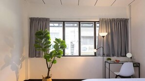 A hotel room with a bed, a desk, a chair, a potted plant, and a window with curtains. - 7-Room Exec House, Rumahku Express, Georgetown (George Town)