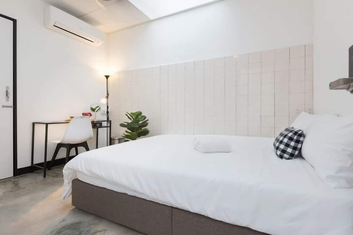 Une chambre d’hôtel moderne, équipée d’un lit, d’un bureau, d’une chaise et d’une plante en pot.