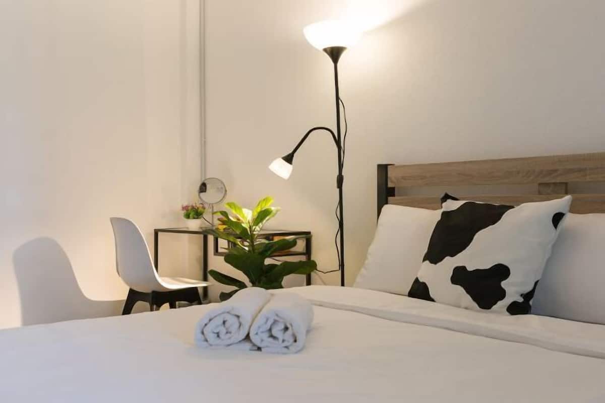 Une chambre d’hôtel avec un lit, un bureau avec une chaise, une lampe et une plante.