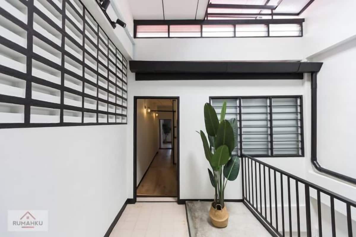Un intérieur moderne avec un escalier, une plante en pot et une vue sur une autre pièce.