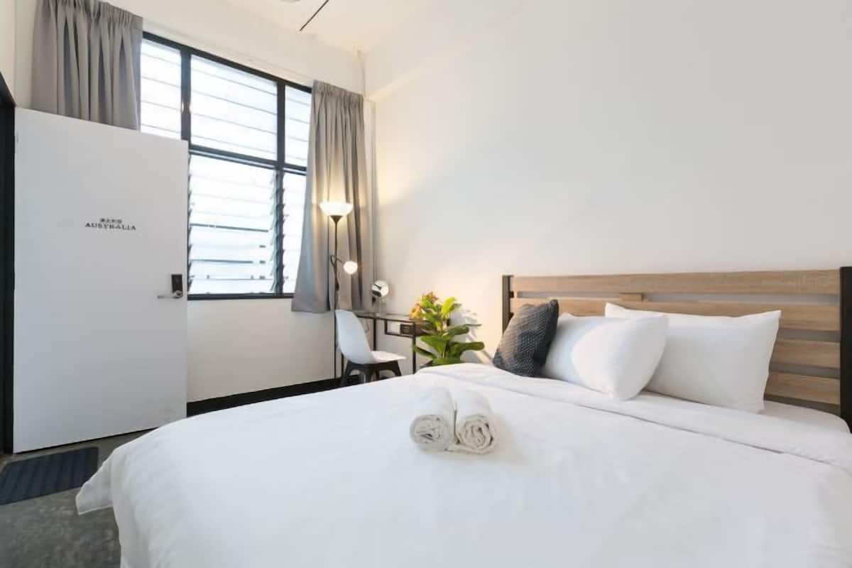 Une chambre d’hôtel avec un lit, un bureau, une chaise et une fenêtre avec des rideaux.