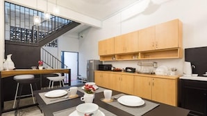 A modern kitchen with a dining table set for two, wooden cabinets, and a staircase. - 7-Room Exec House, Rumahku Express, Georgetown (George Town)