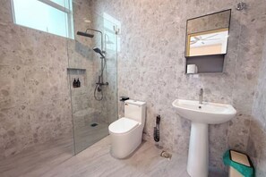 A modern bathroom with a glass-enclosed shower, a toilet, and a pedestal sink.