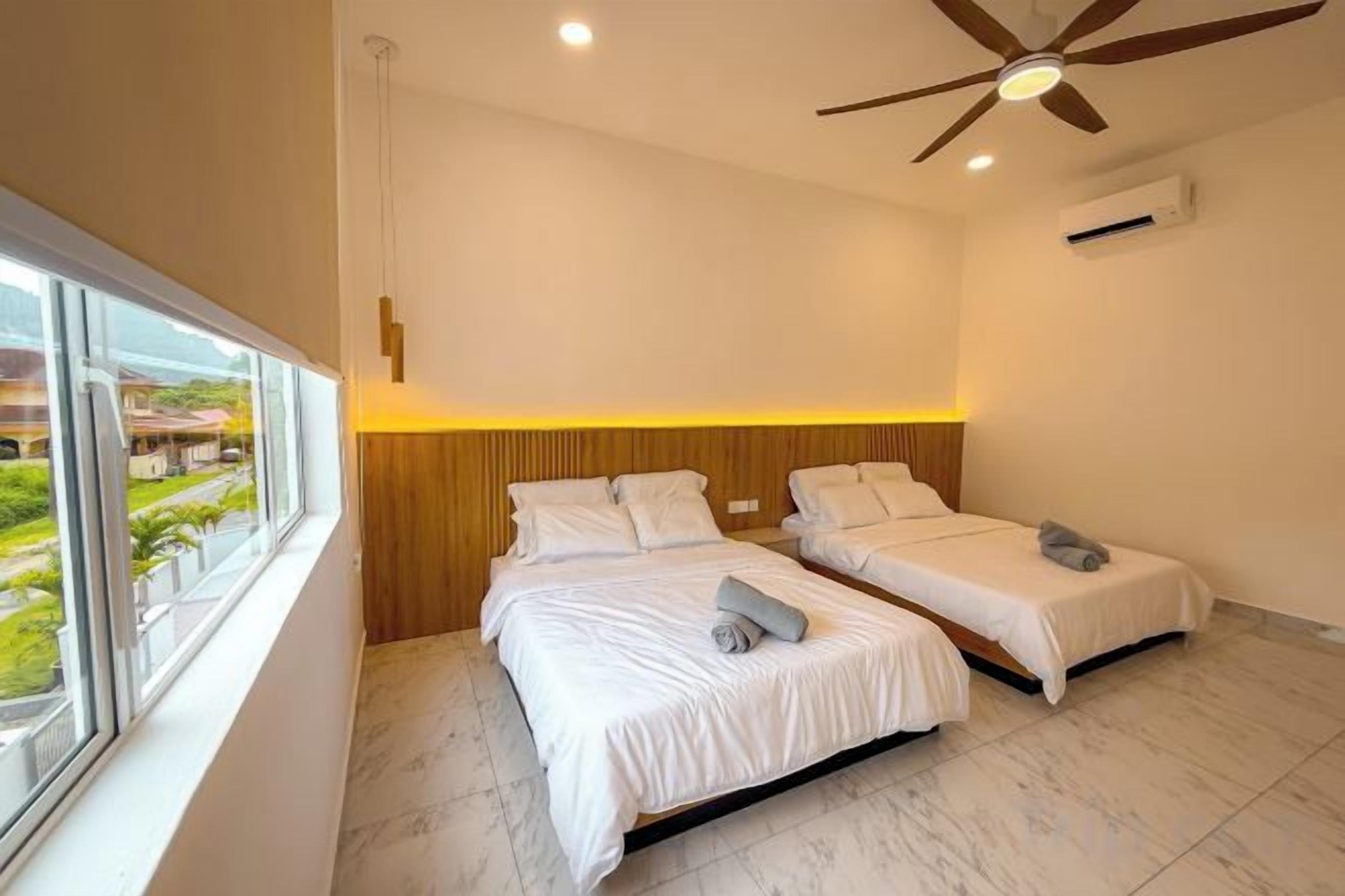 A bedroom with two beds, a ceiling fan, and a window with a view.