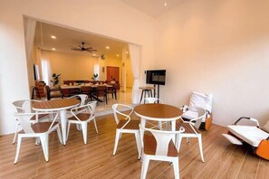 A modern living room with a dining area, featuring white furniture and a wooden floor.