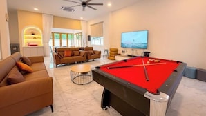 A spacious living room with a pool table, comfortable seating, a television, and a ceiling fan. - Aesthetic Muji Pool Villa in Ipoh 5BR 24Pax (Tambun)