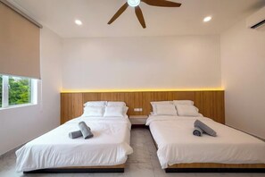 Habitación de hotel con dos camas, ventilador de techo y ventana.