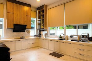 Une cuisine moderne avec des meubles blancs, un four encastré et une fenêtre qui laisse entrer la lumière naturelle.