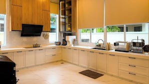A modern kitchen with white cabinets, a built-in oven, and a large window with a view of greenery. - Aesthetic Muji Pool Villa in Ipoh 5BR 24Pax (Tambun)