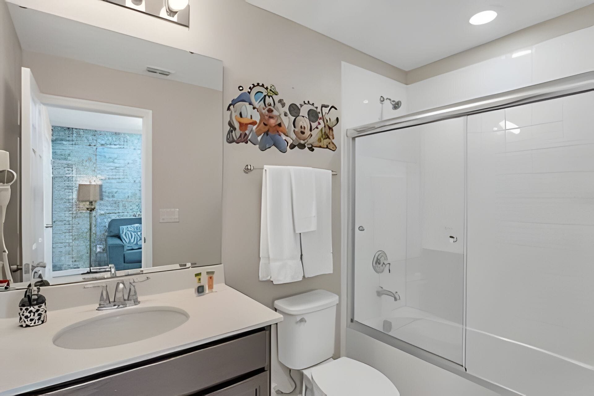 Une salle de bain moderne avec un grand miroir, un lavabo, des toilettes et une douche à parois de verre.