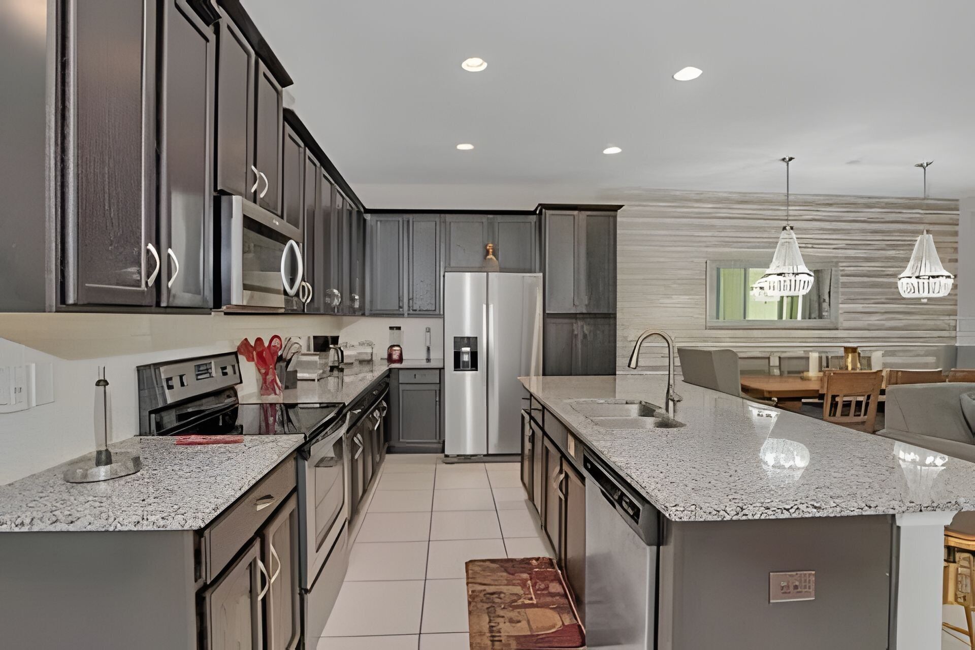 A modern kitchen with granite countertops, stainless steel appliances, and dark cabinetry.