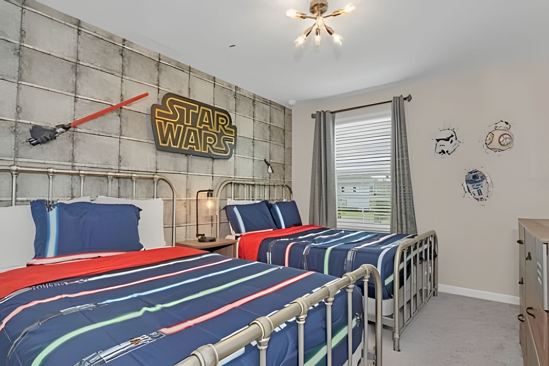Un dormitori amb temàtica de Star Wars, amb dos llits, un cartell de Star Wars i una finestra amb persianes.