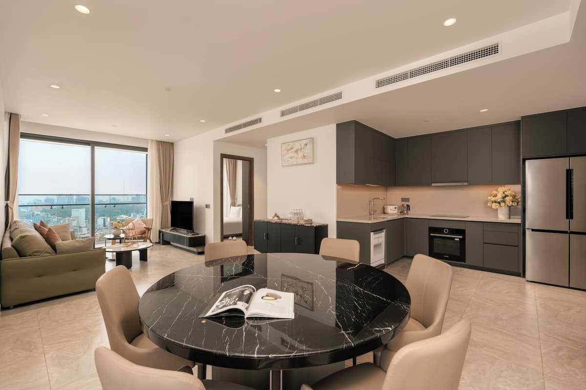 Una sala de estar moderna con una mesa redonda de mármol negro, un sofá beige y un amplio ventanal con vista a la ciudad.