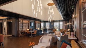 Un hall amplio con techo alto, muebles modernos y vistas a la ciudad.