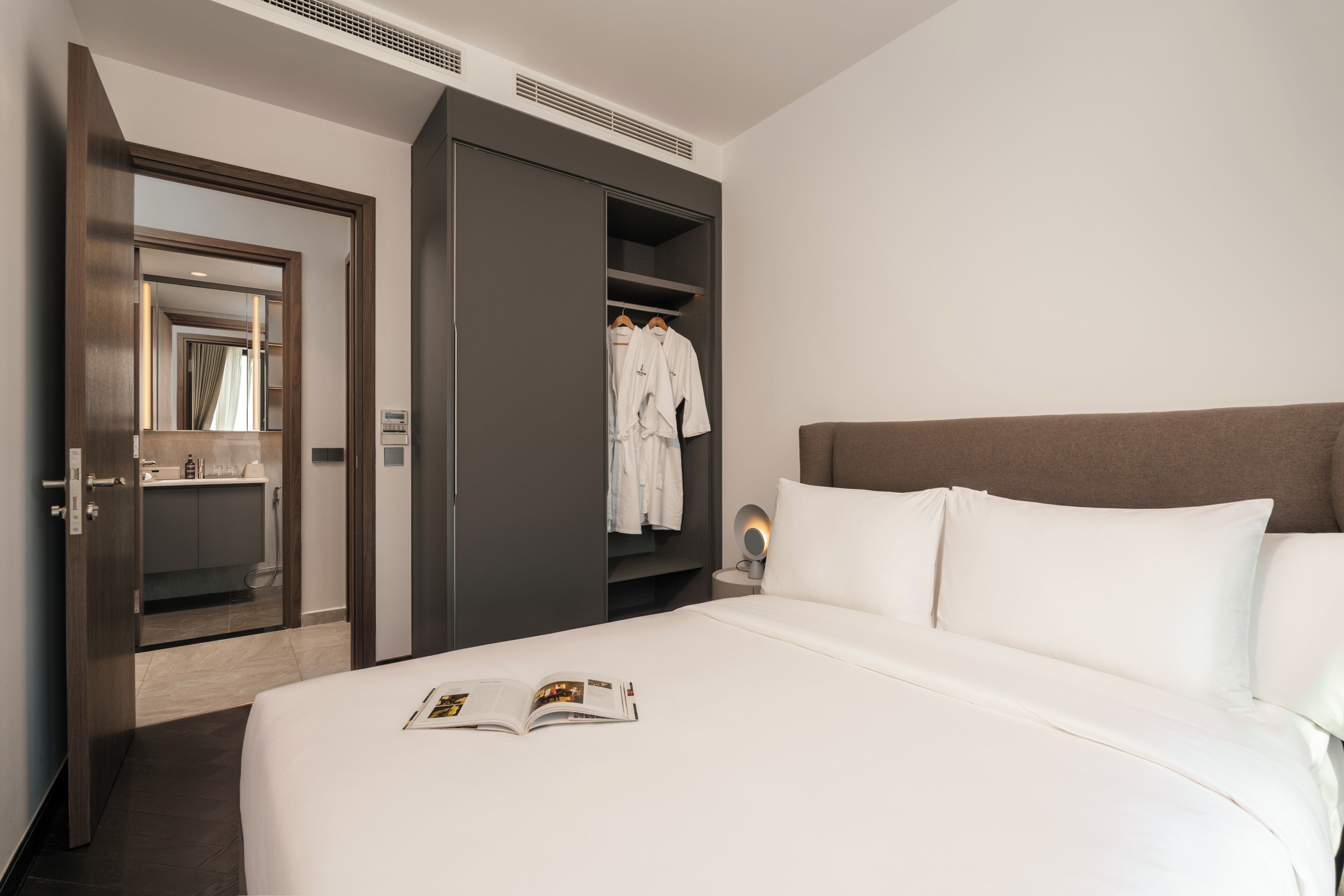 A hotel room with a bed, a wardrobe, a mirror, and a nightstand.