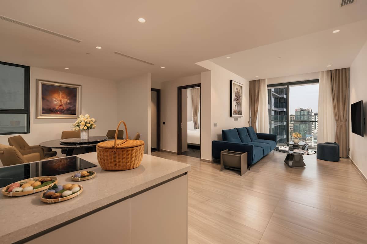 Una sala de estar moderna con un sofá, una mesa de comedor y una zona de cocina con un cesto y cuencos para comida.