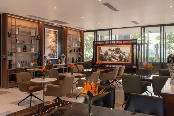 A modern hotel lobby with a large painting, comfortable seating, and a well-organized bookshelf.