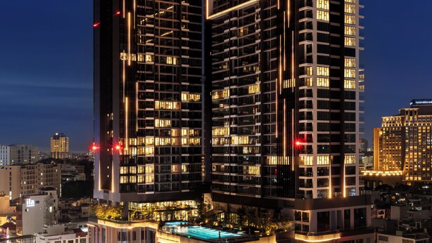 Un hotel de gran altura con el rótulo 'Lancaster', varios pisos y ventanas iluminadas.