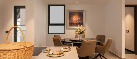 A modern dining area with a round table, chairs, a basket, and a vase with flowers.