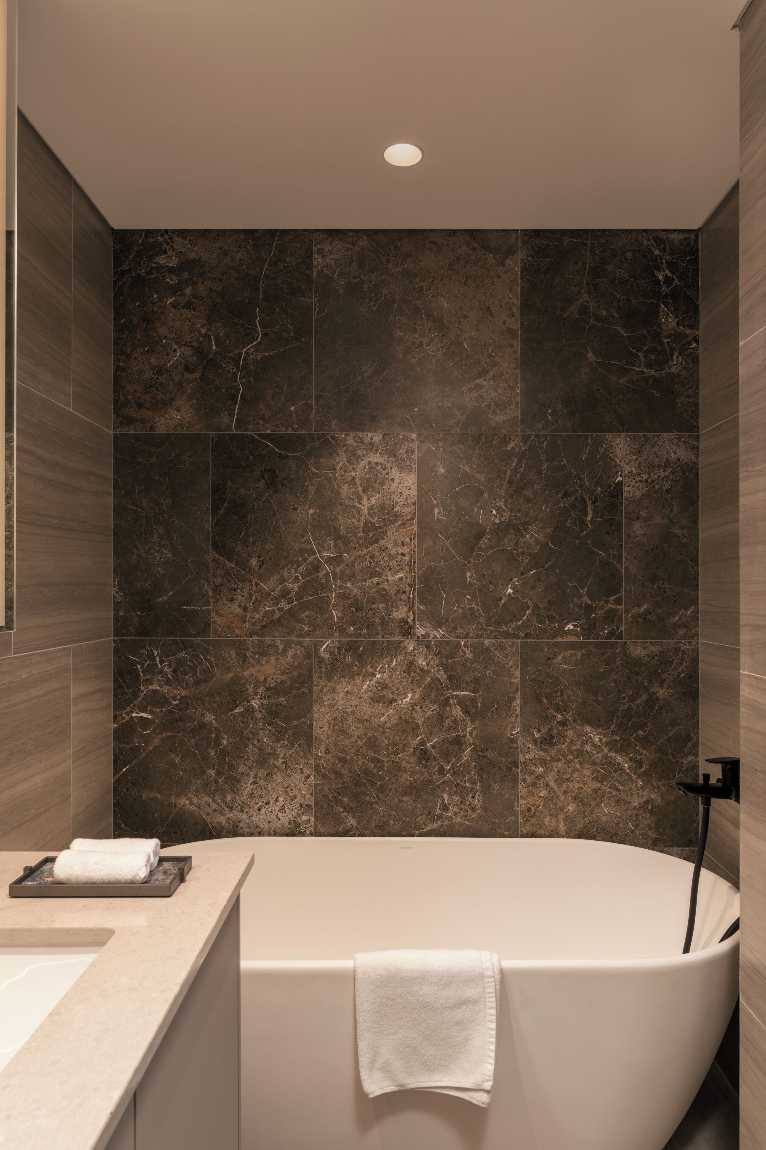 A modern bathroom with a freestanding bathtub, a vanity with a sink, and a towel rack.
