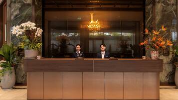 A reception desk with two staff members, a marble wall, and a sign that reads 'Lancaster Legacy.'