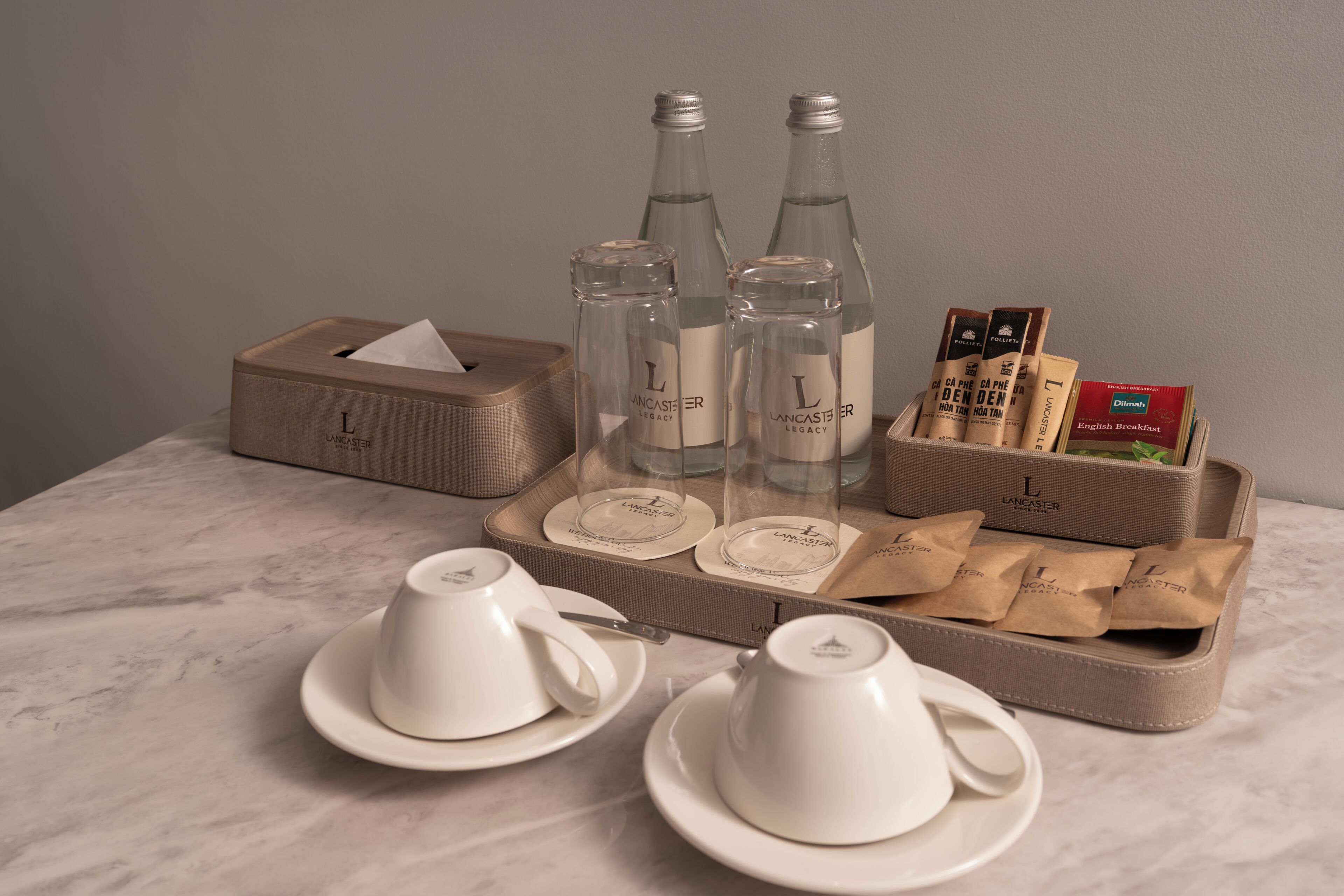 A tray with two cups, two bottles, a tissue box, and a box of English Breakfast tea.