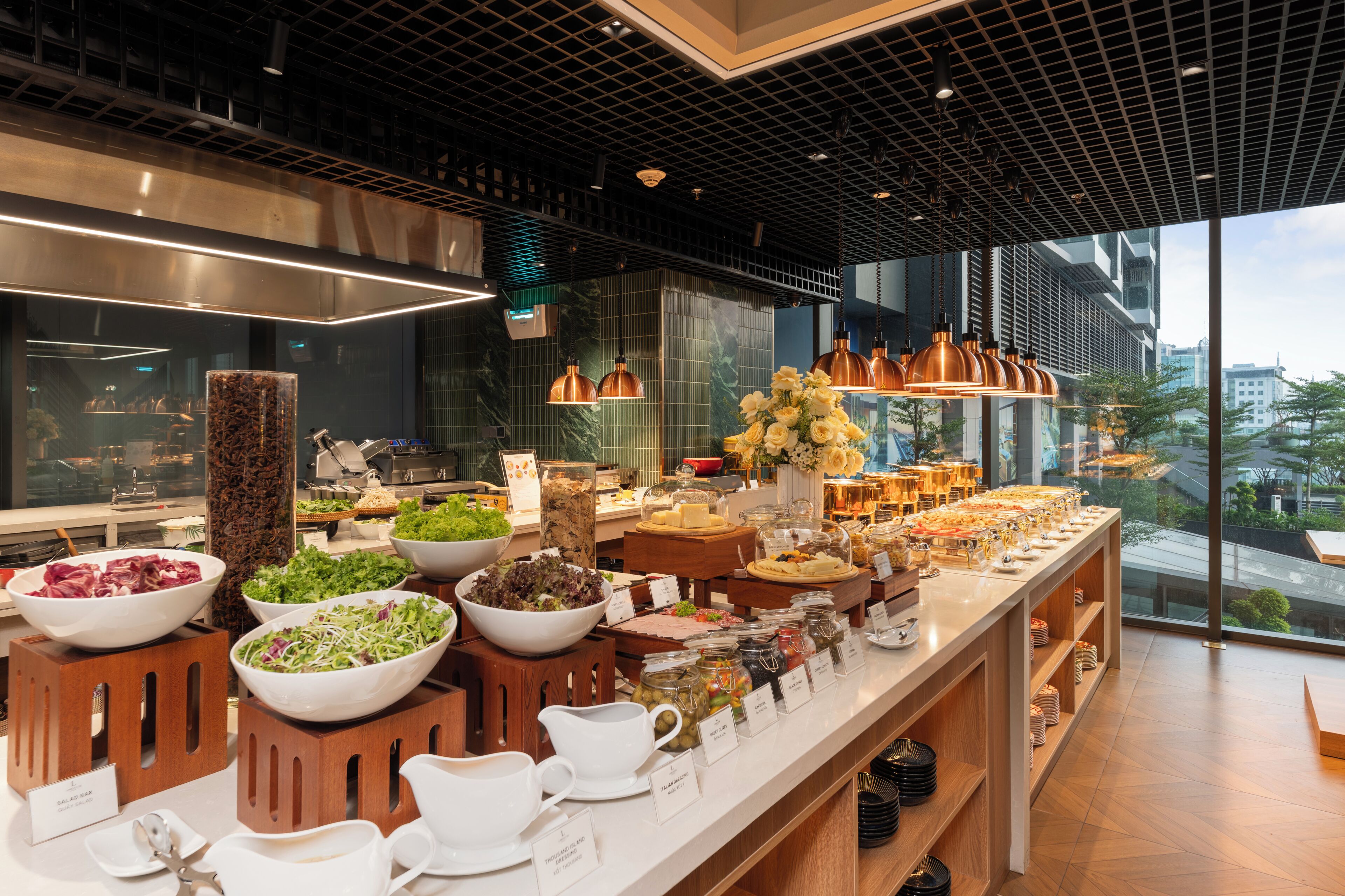 A buffet with various food items and a view of the city through large windows.