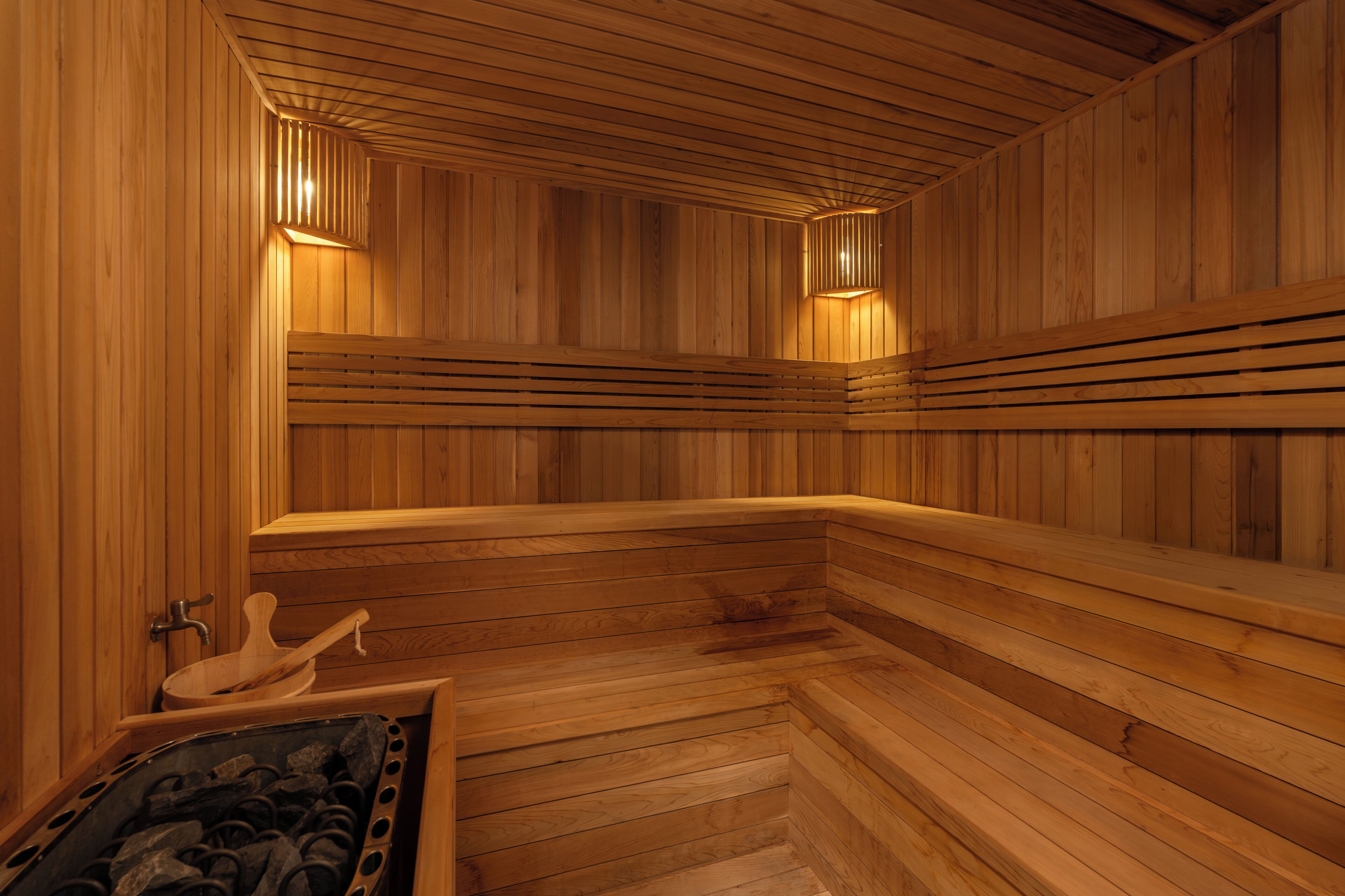 A wooden sauna with benches, a bench with a towel, and a wooden bench with a towel.