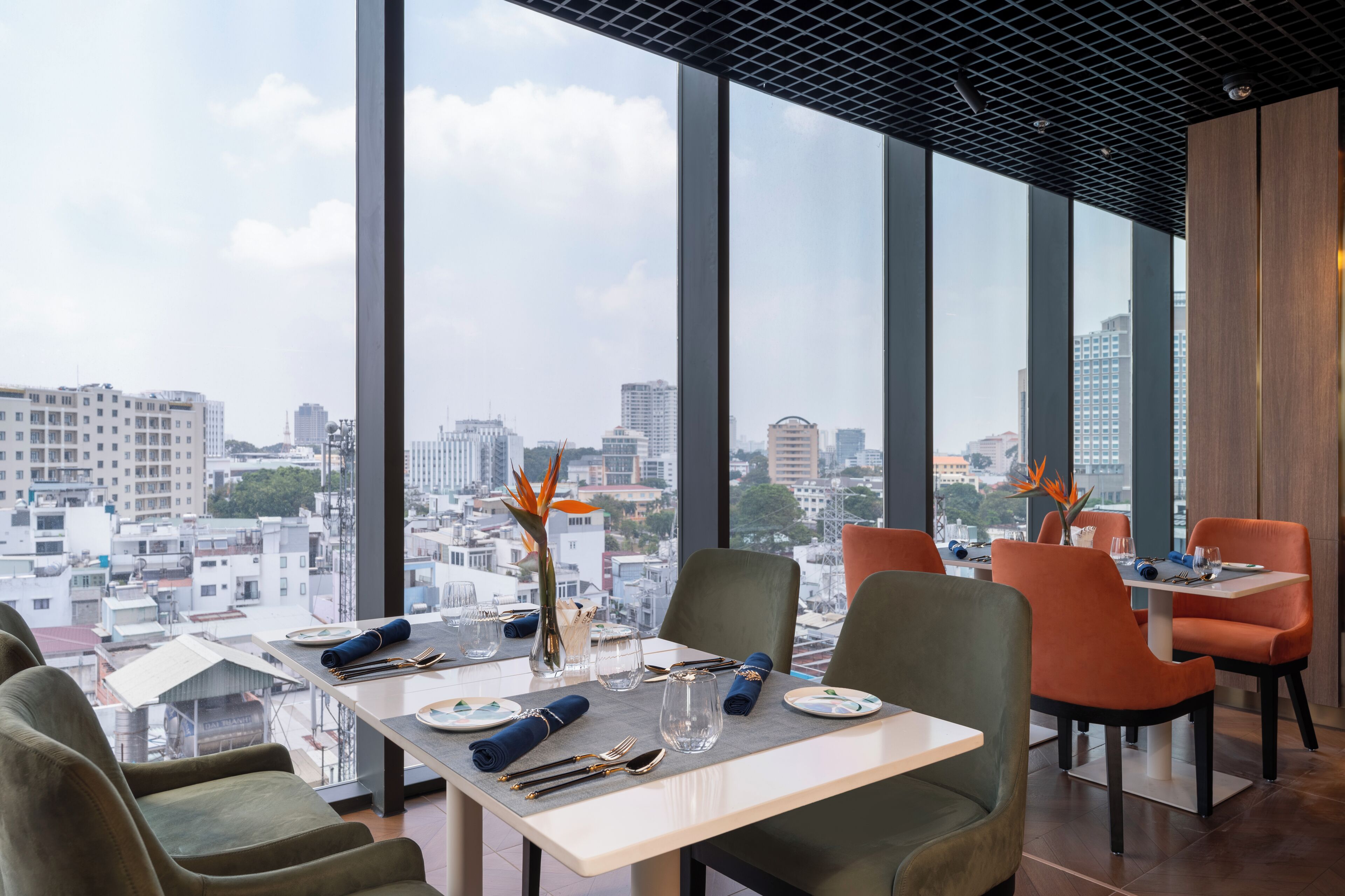 A modern restaurant with large windows, city views, and a table set with cutlery and glasses.