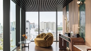 Una habitación moderna con un ventanal amplio, una zona de estar circular y una consola de madera.