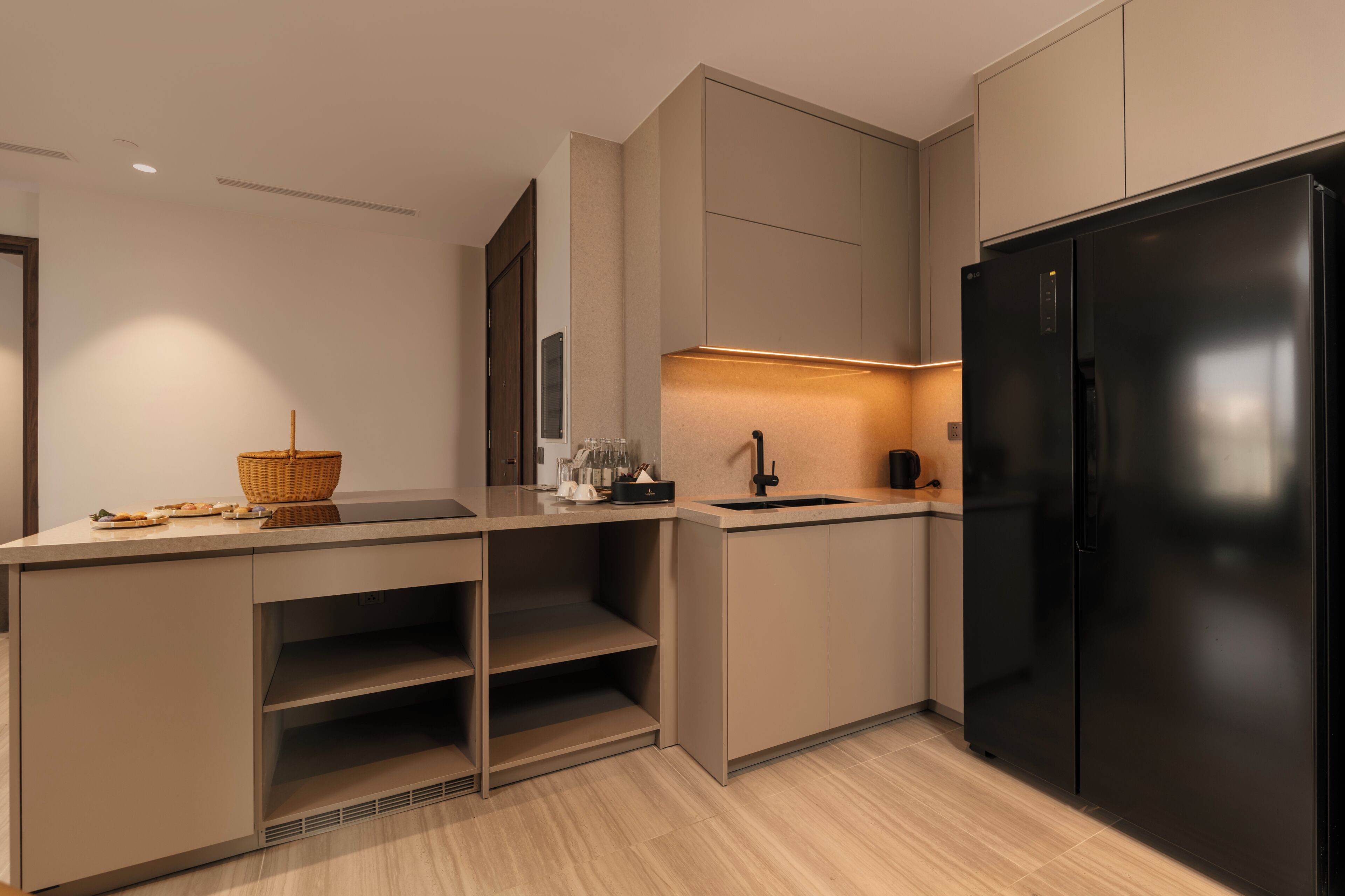 A modern kitchen with a black refrigerator, built-in cabinets, and a light-colored countertop.
