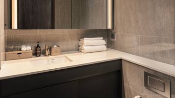 A modern bathroom with a large mirror, a toilet, and a vanity with a sink and storage.