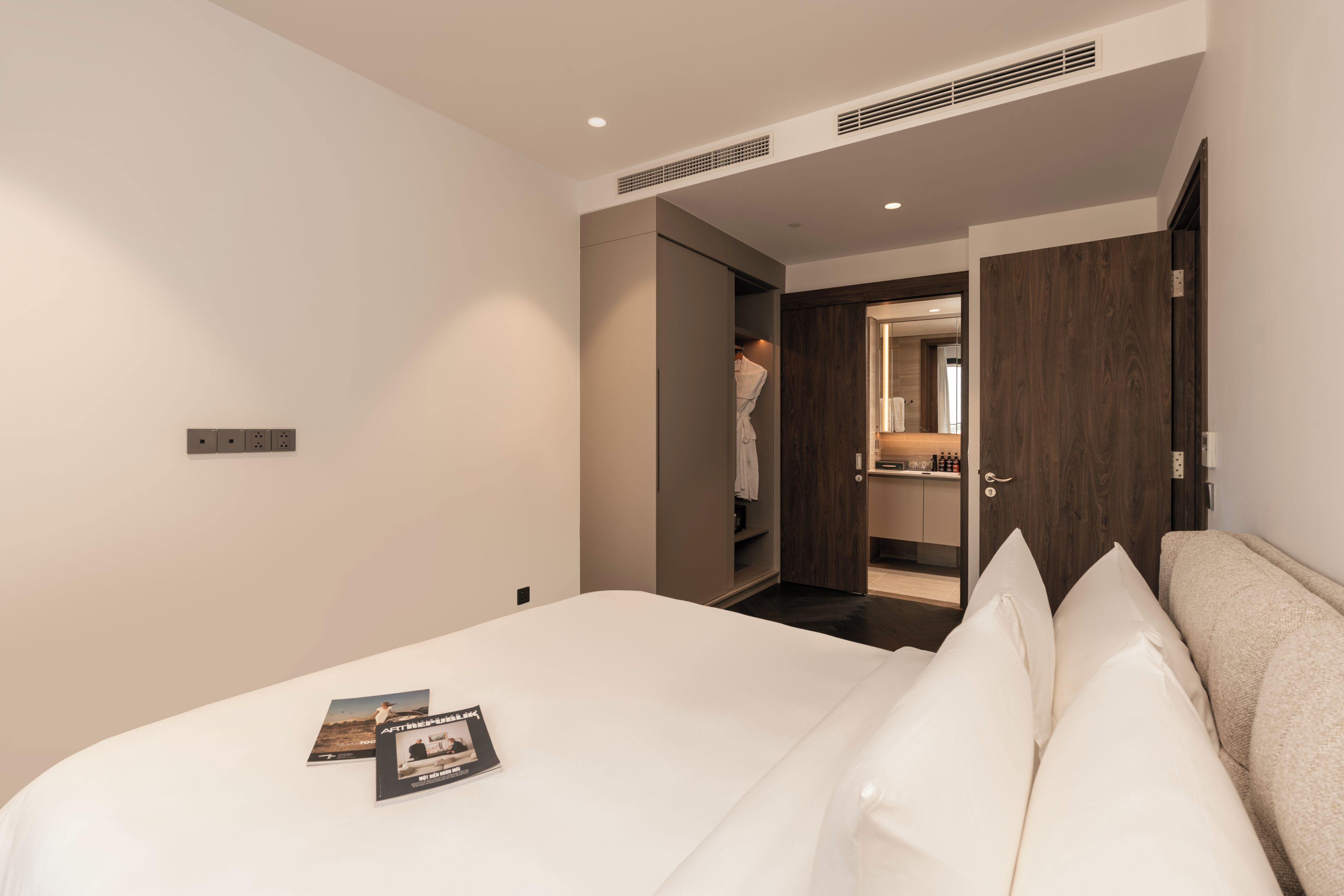 Une chambre d’hôtel avec un lit, une armoire et une salle de bain, visibles à travers une porte ouverte.