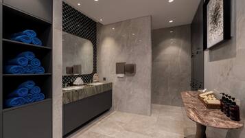 Une salle de bain moderne avec des carreaux de marbre, une étagère intégrée où sont rangées des serviettes bleues, un meuble-lavabo avec un plan de travail en marbre et un espace douche.