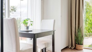 Une pièce comprenant une table à manger, des chaises, une plante en pot et une vue par la fenêtre.