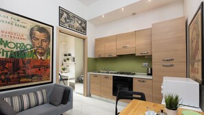 A modern kitchen with wooden cabinets, a dining table with chairs, and a sofa in the living area.