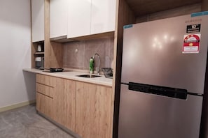 Eine KĂŒche mit HolzschrĂ€nken, einem EdelstahlkĂŒhlschrank, einer SpĂŒle und einer Mikrowelle.