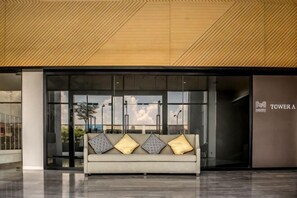 A modern lobby with a sofa, large windows, and a sign for 'TOWER A'.