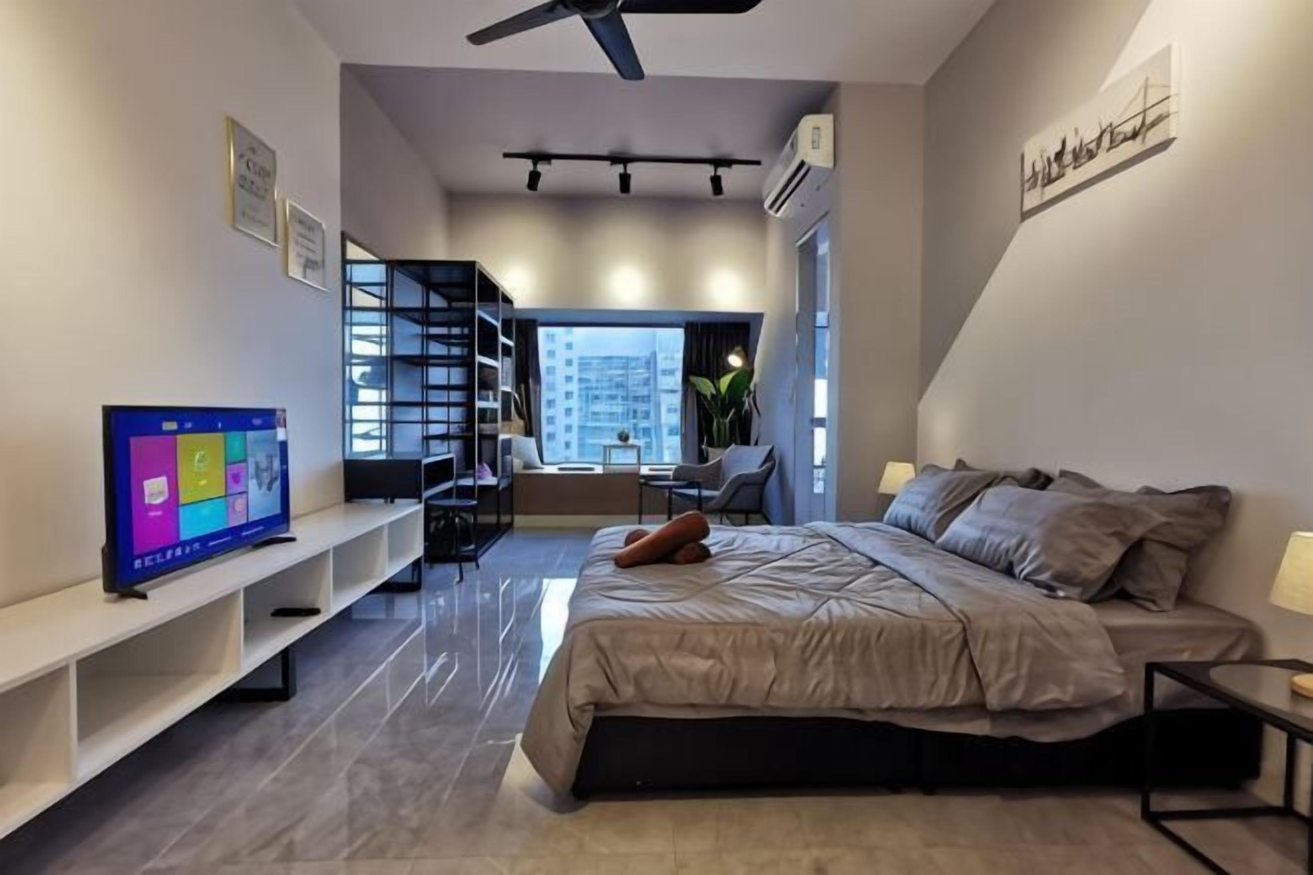 Ein modernes Schlafzimmer mit Bett, Fernseher, Schreibtisch und einer Treppe zu einem Außenbereich.