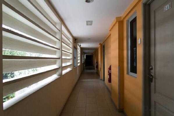A corridor with a fire extinguisher, a door, and a window with blinds. - Hotel WW KL (Kuala Lumpur)