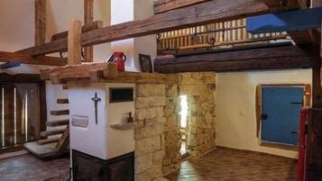 A rustic interior with exposed wooden beams, a stone wall, a fireplace, and a blue door.