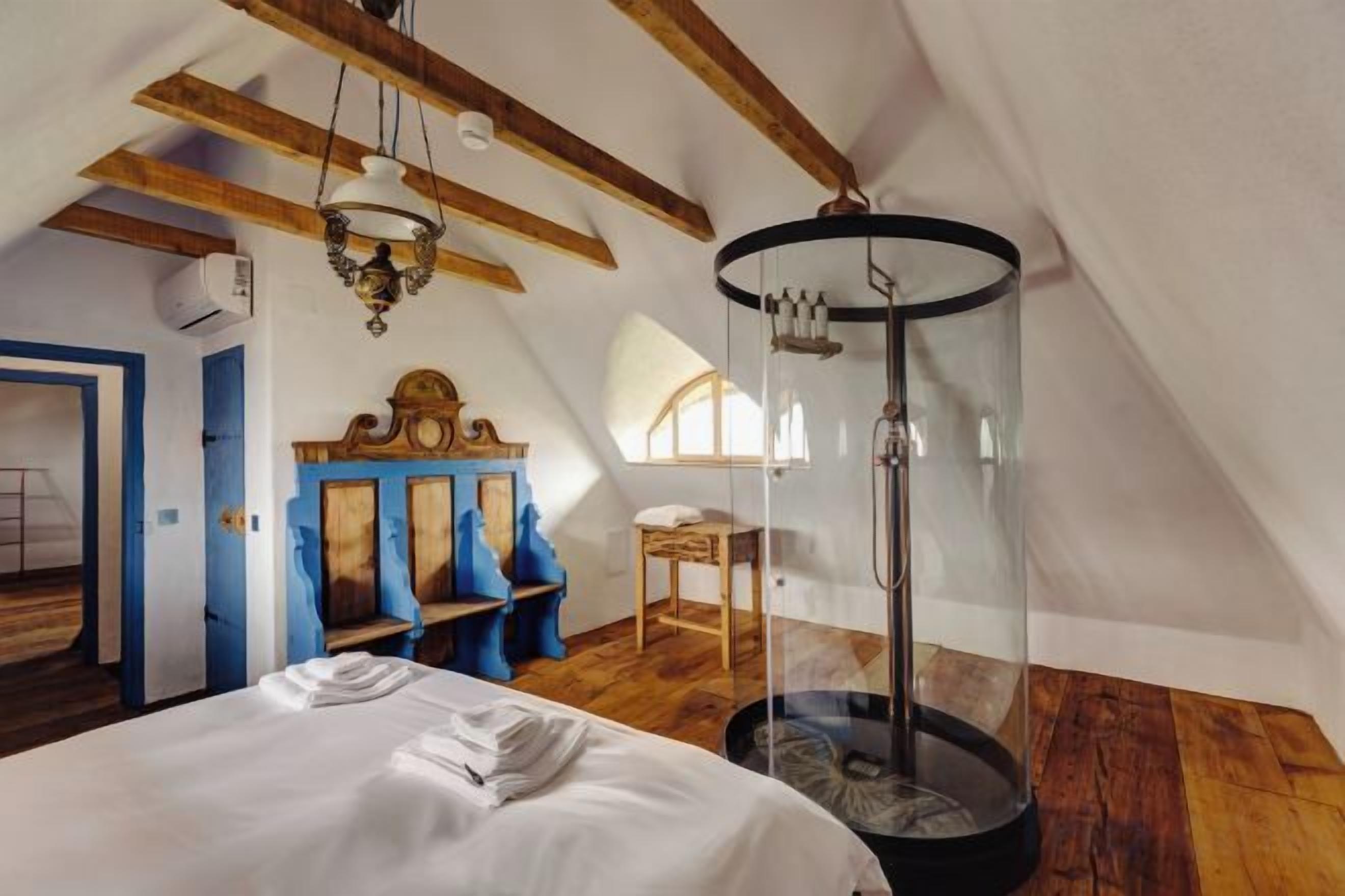 A bedroom with a bed, a circular window, and a wooden ceiling.