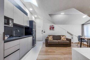 A modern kitchen with built-in appliances, a dining area with a table and chairs, and a living space with a sofa.