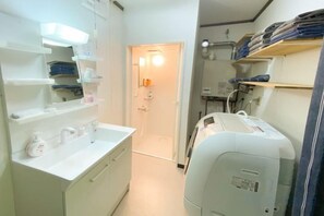 A narrow hallway with a white sink, mirror, and shelves on one side, and a medical device on the other. - Sola st. Inn Noboribetsu (Noboribetsu)
