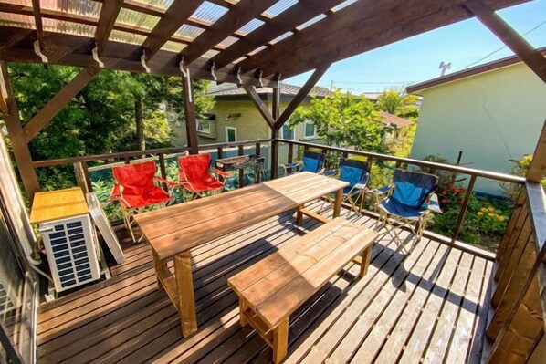 A wooden deck with a table and chairs, a covered area, and a view of a residential area. - Sola st. Inn Noboribetsu (Noboribetsu)