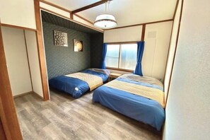 A compact room with two beds, a ceiling light, a window with curtains, and a wall-mounted picture. - Sola st. Inn Noboribetsu (Noboribetsu)