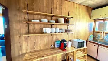Una cocina con estantes de madera, un microondas y una cafetera.