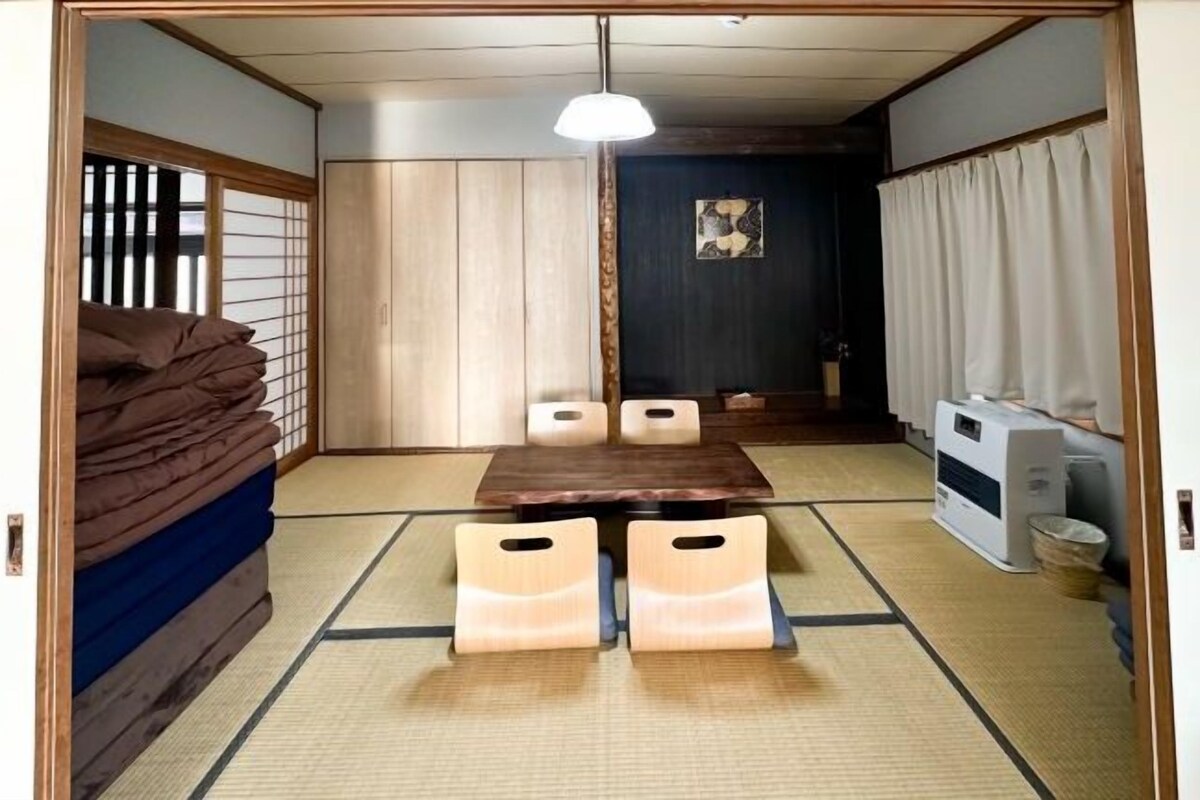 Una tradizionale stanza giapponese con pavimenti in tatami, un tavolino con cuscini, un termosifone e porte scorrevoli.