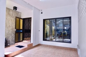 A spacious room with a large sliding glass door, a staircase leading to an upper level, and a tiled floor. - P'Ja House by Lorenzo Property (Hat Yai)